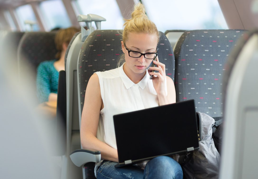 Produtividade na empresa mulher branca com os cabelos loiros e usando óculos de grau trabalha com o notebook no trajeto de ônibus fretado.